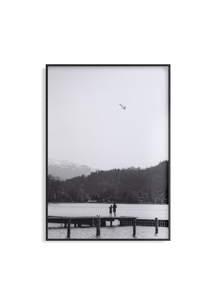 Analogfotografie Kunstdruck von Anna Fleischmann – Vater und Kind beim Drachensteigen am Tegernsee Steg. Zeitlos, emotional, auf echtem Schwarzweiß-Film. Limitiert, kein Massenprodukt.